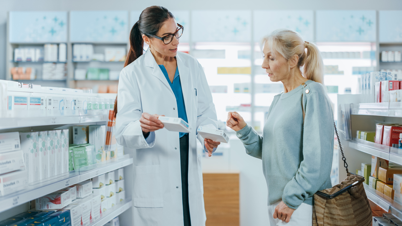 Pharmacist helping a women decide between two medications in a pharmacy