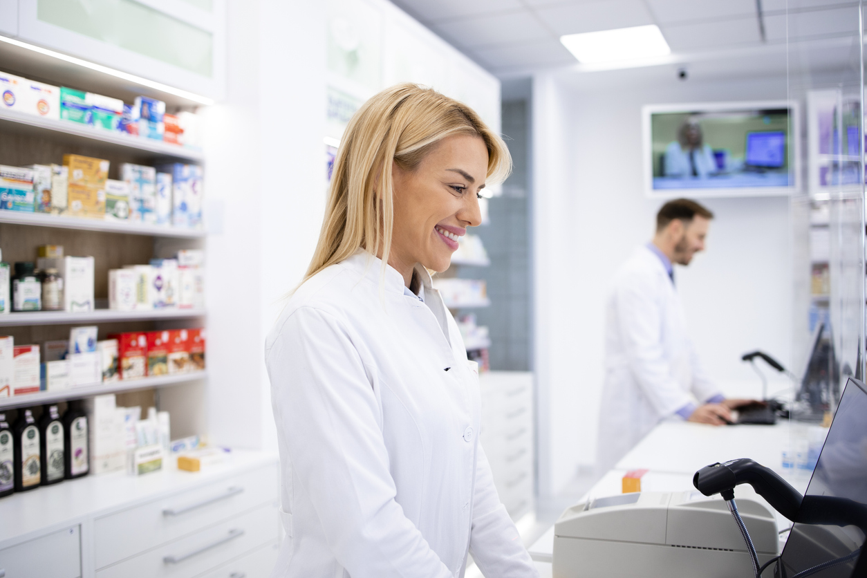 Pharmacist at checkout smiling at customer