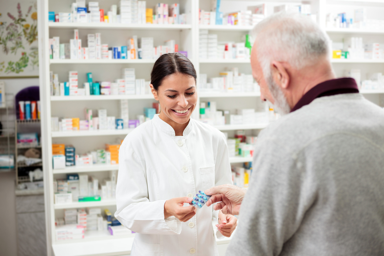 Female pharmacist giving medications to senior customer